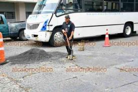 Xalapa, Ver., 9 de diciembre de 2025.- Ante la dejadez de autoridades, ciudadanos rellenan baches con chapopote en la zona del Ferrocarrilero. A cambio piden una moneda.
